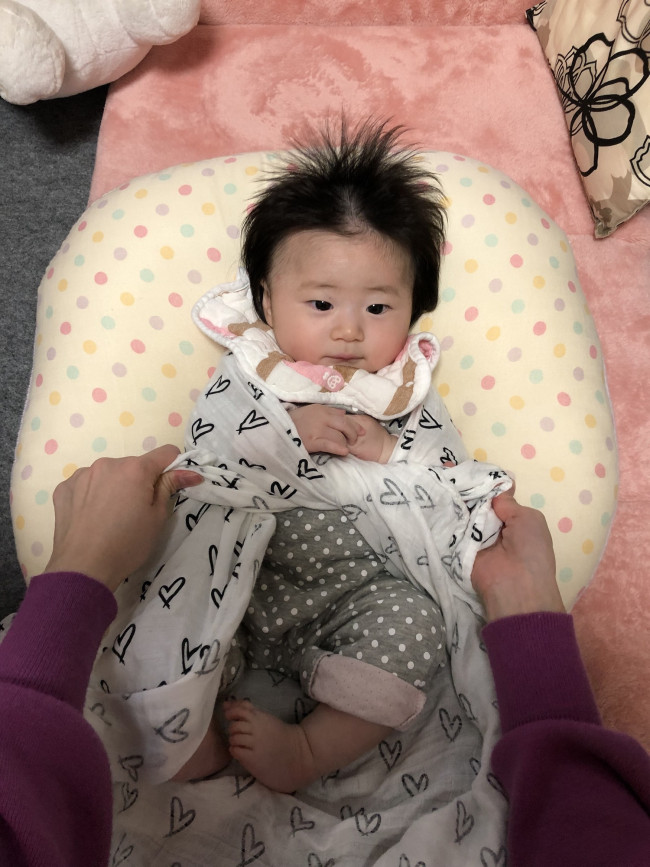 赤ちゃんの肘を支えながら、手の下で布の両端を2回しっかり結びます。まだ手遊びしない赤ちゃんなら、首のすぐ下で結んでしまってもOK。きつく結んで、苦しくならないように